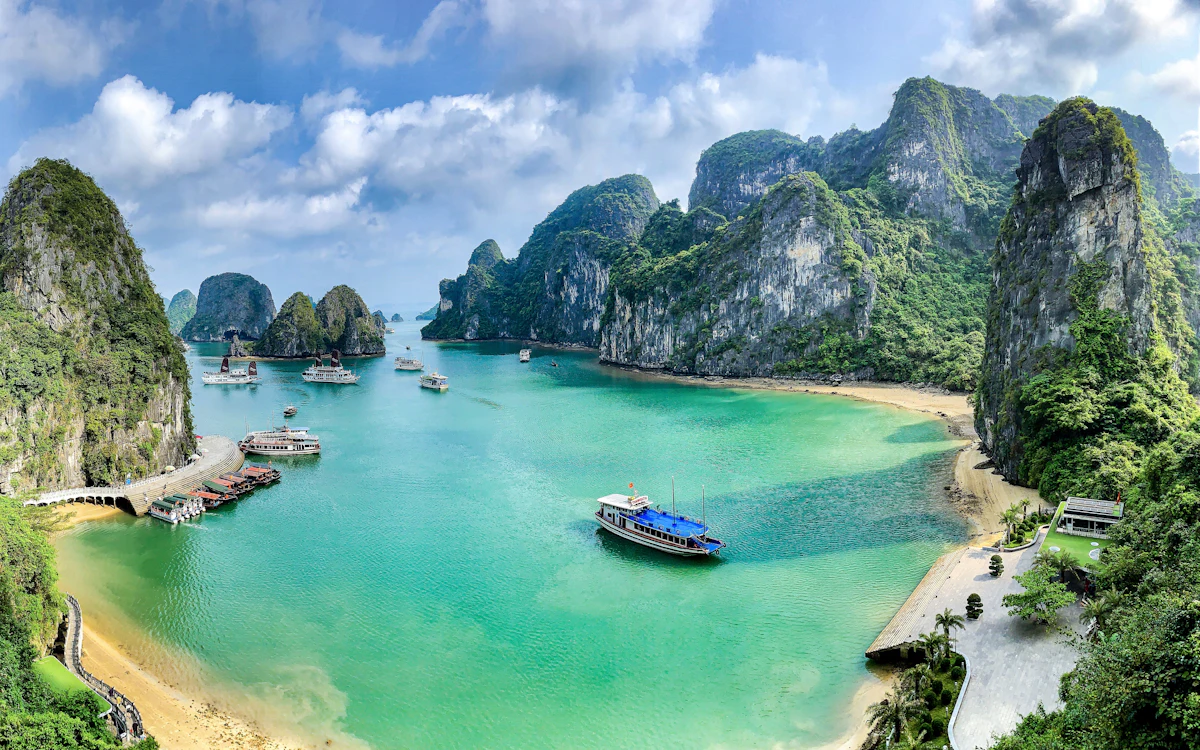 Boote auf dem türkisfarbenen Wasser der Ha Long Bay, umgeben von Kalkstein-Karstinseln