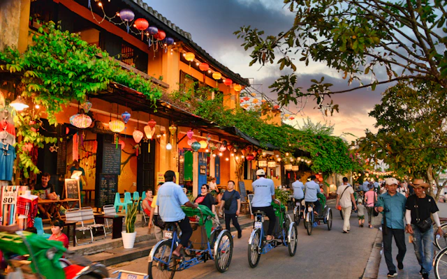 Radfahrer zwischen beleuchteten Häusern und Laternen in Hoi An