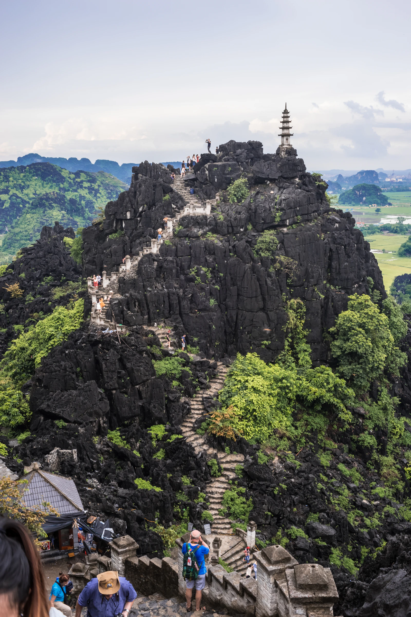 Steintreppe am felsigen Hang-Mua-Aussichtsberg mit mehrstöckigem Turm und grüner Karstlandschaft